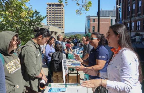 Students interact with employers outdoors at tables.